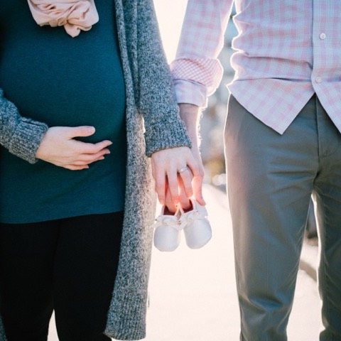 An expectant couple holding baby shoes